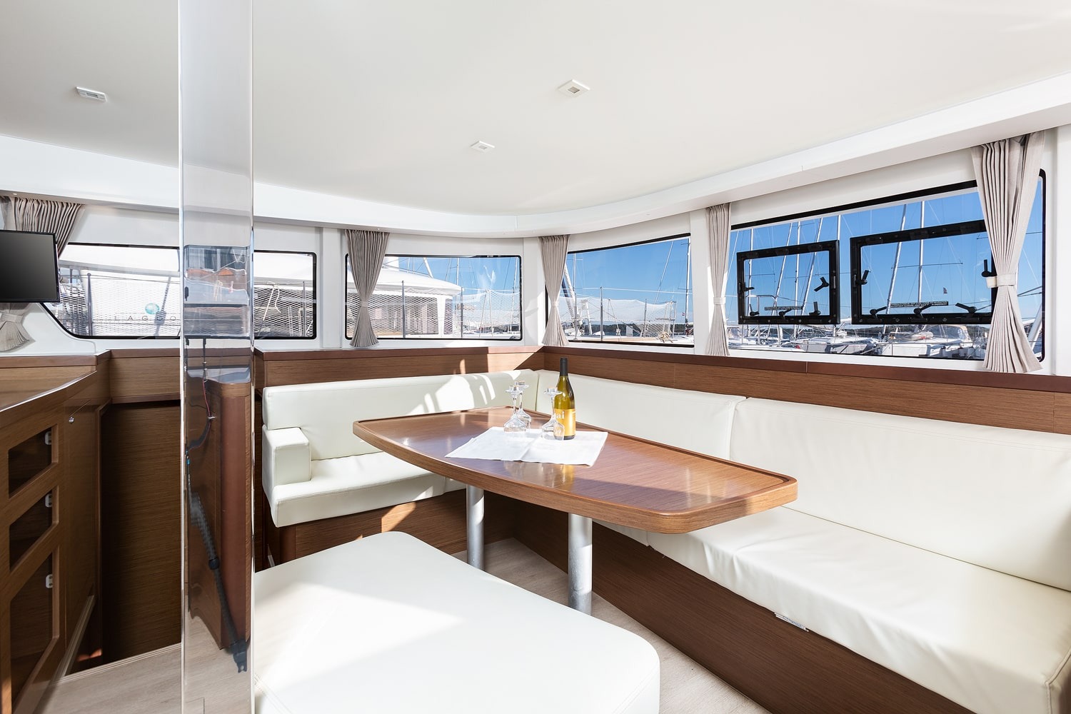Dining area in the Lagoon 42 saloon, cream upholstery and polished wood table set with glasses