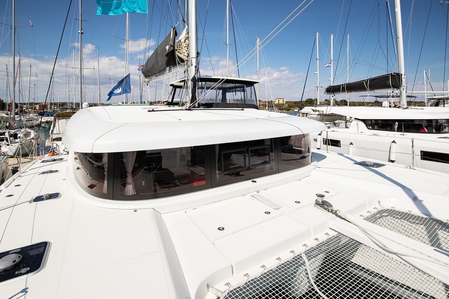 Foredeck of the Lagoon 42 looking aft over the curved saloon windows, trampolines and anchor windlass in view