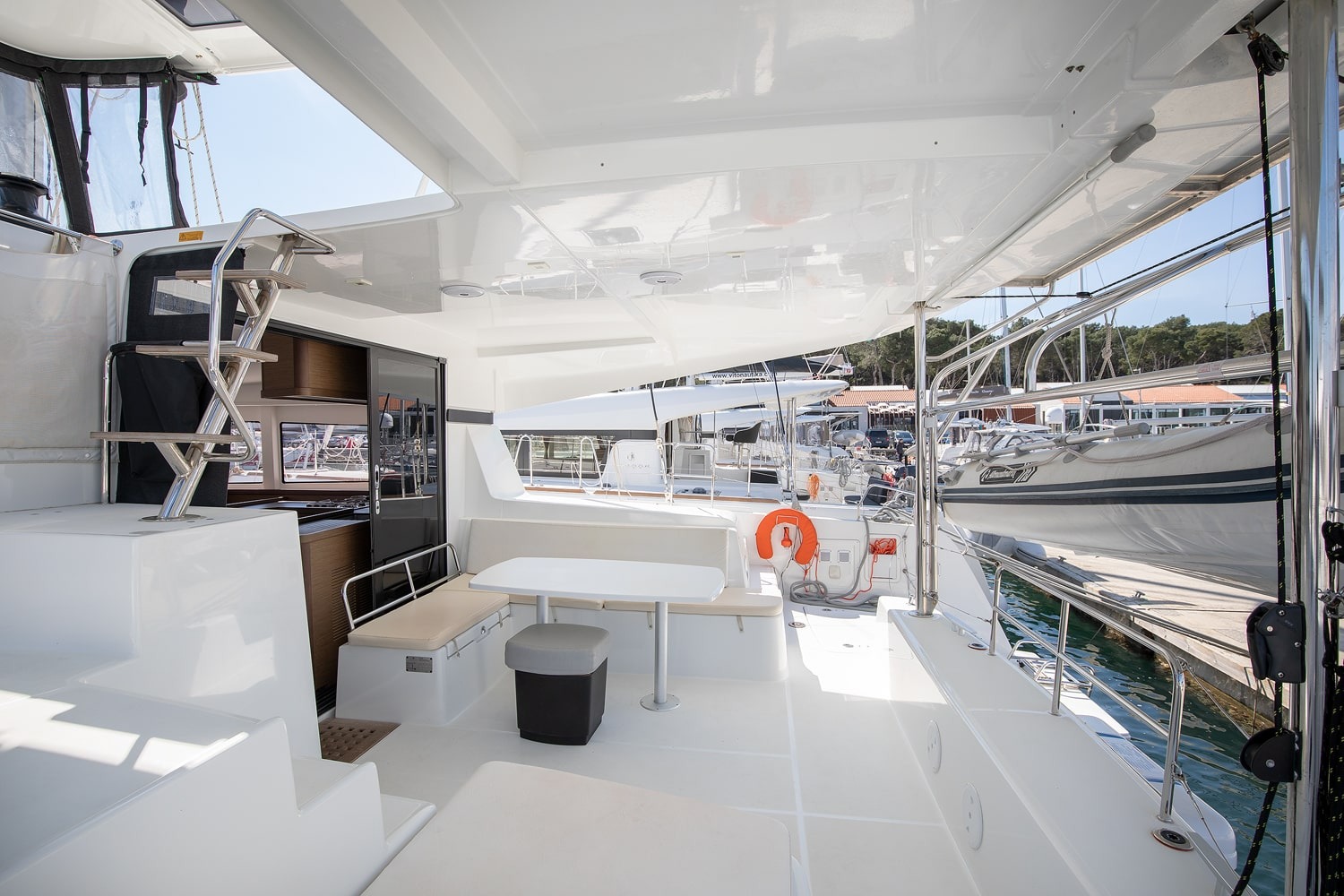 Shaded cockpit of the Lagoon 42 with dining table, bench seating and steps up to the helm