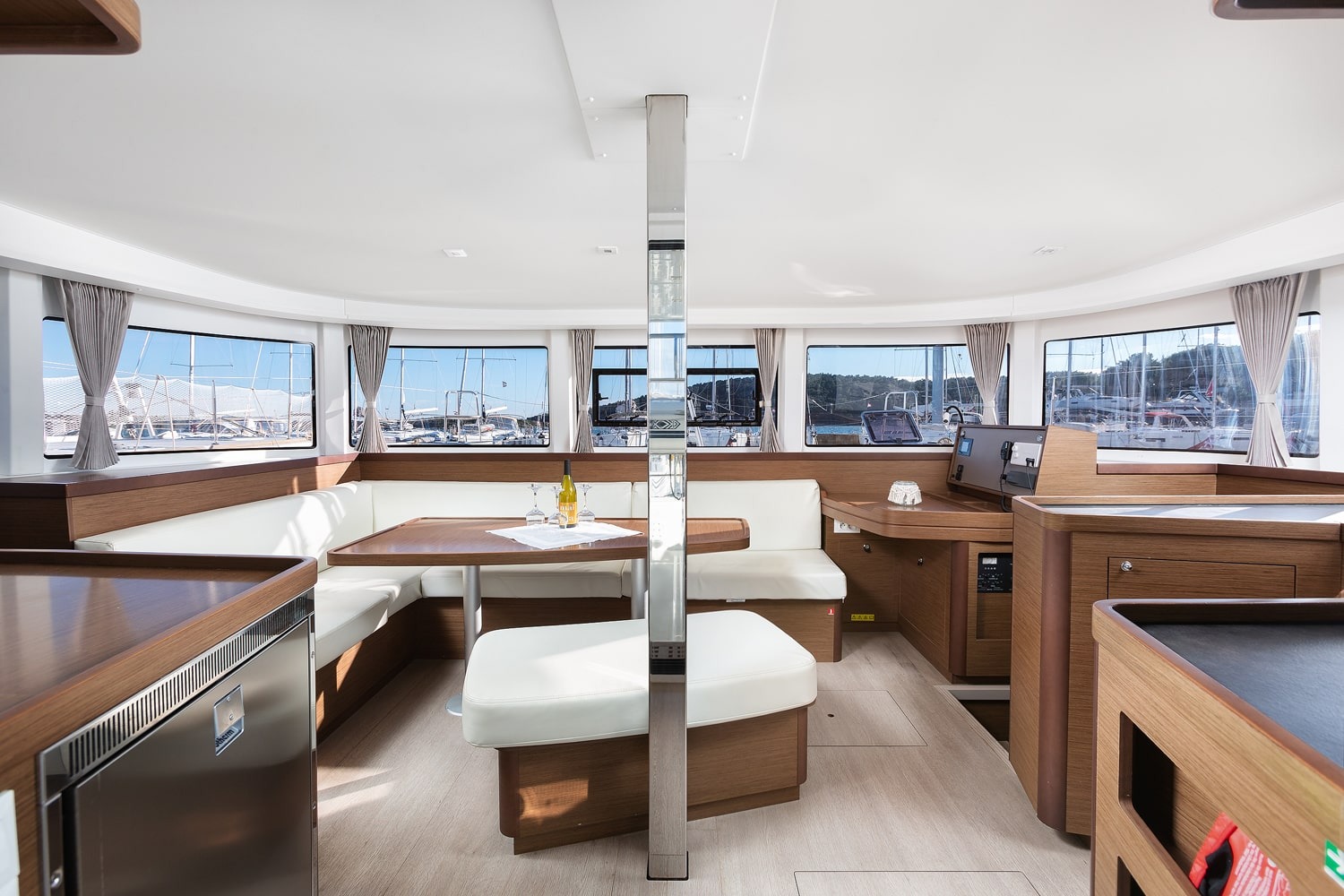 Saloon of the Lagoon 42 with wraparound windows, U-shaped settee and wooden dining table