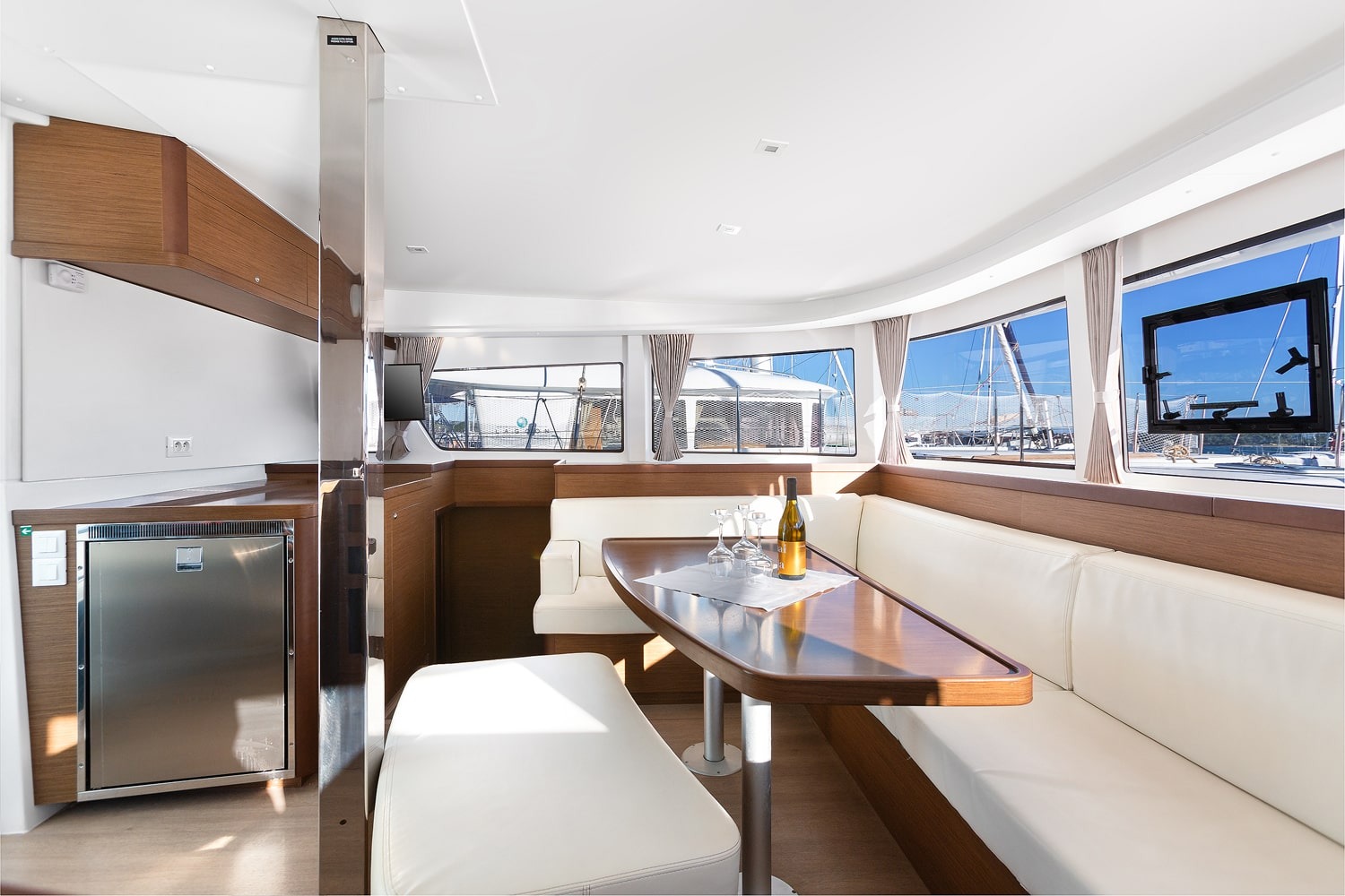 Saloon settee and table of the Lagoon 42 with fridge alongside and panoramic windows above