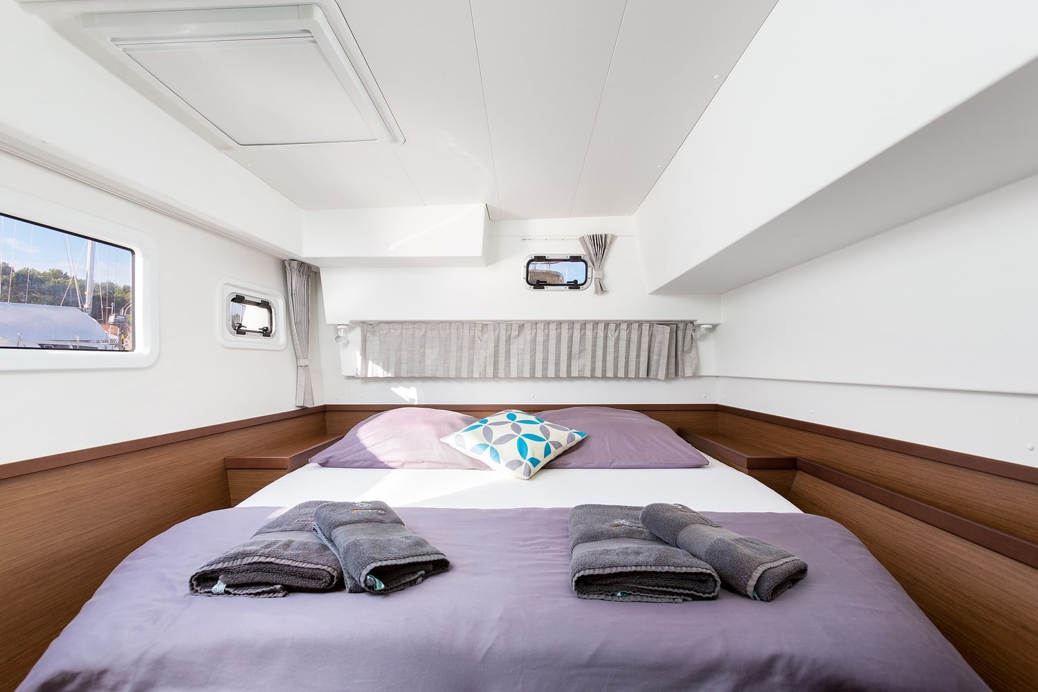 Double cabin of the Lagoon 42 with hull window, opening ports and bed made up with towels
