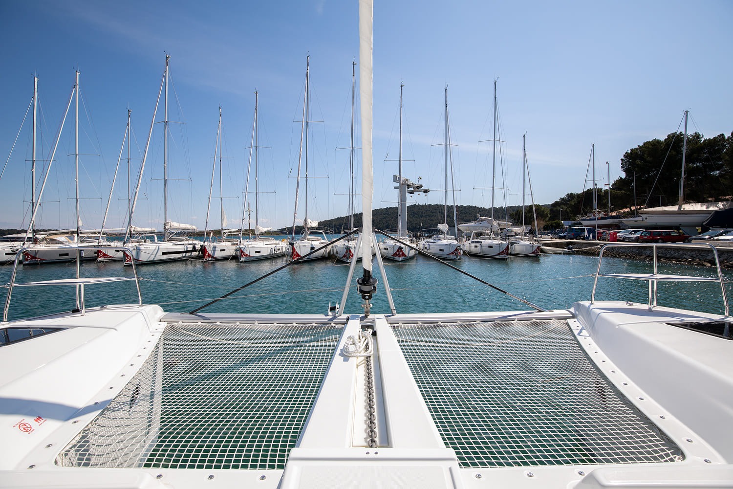 Foredeck of the Lagoon 46 with twin trampolines between the hulls, anchor chain and mast, looking forward across the marina