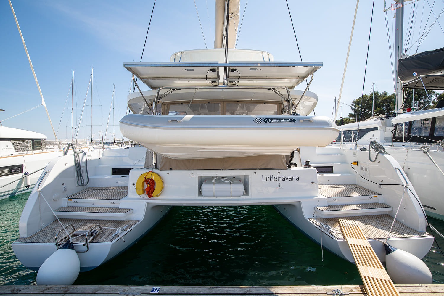 Little Havana, a Lagoon 46 catamaran moored stern-to in ACI Marina Pomer, with her name on the transom, a tender hanging on davits and teak bathing platforms on both hulls