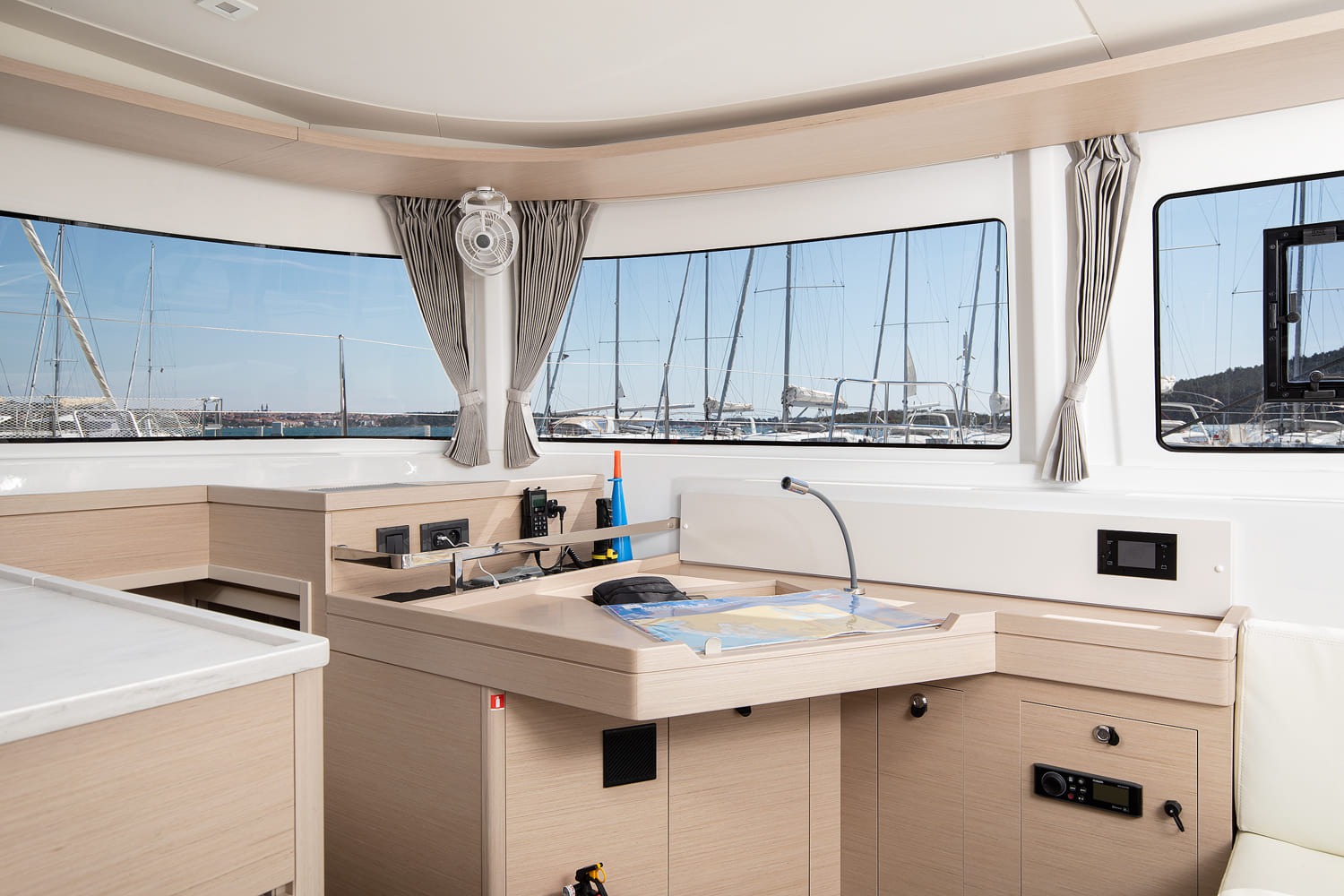 Navigation station of the Lagoon 46 with chart table, VHF radio, instrument panel and reading light below the saloon windows