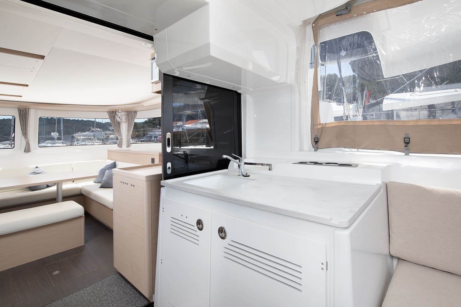 Cockpit wet bar of the Lagoon 46 with sink and gas hob, serving hatch to the galley and cushioned seating either side