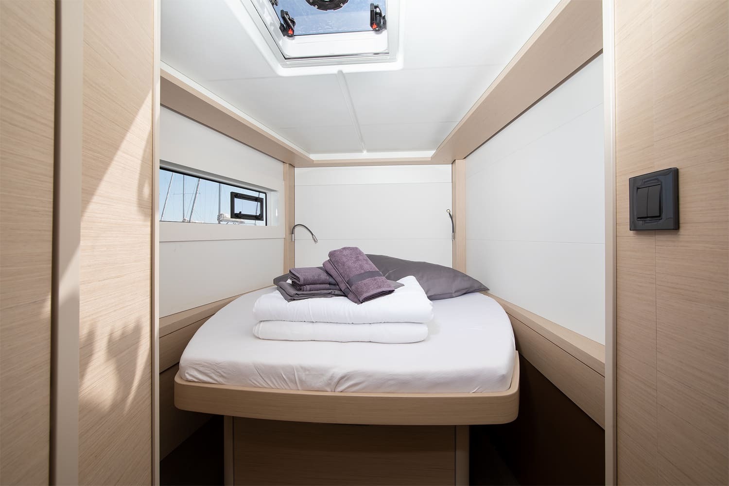 Forward double cabin on the Lagoon 46 with island berth, hull window, reading light and overhead hatch above the bed
