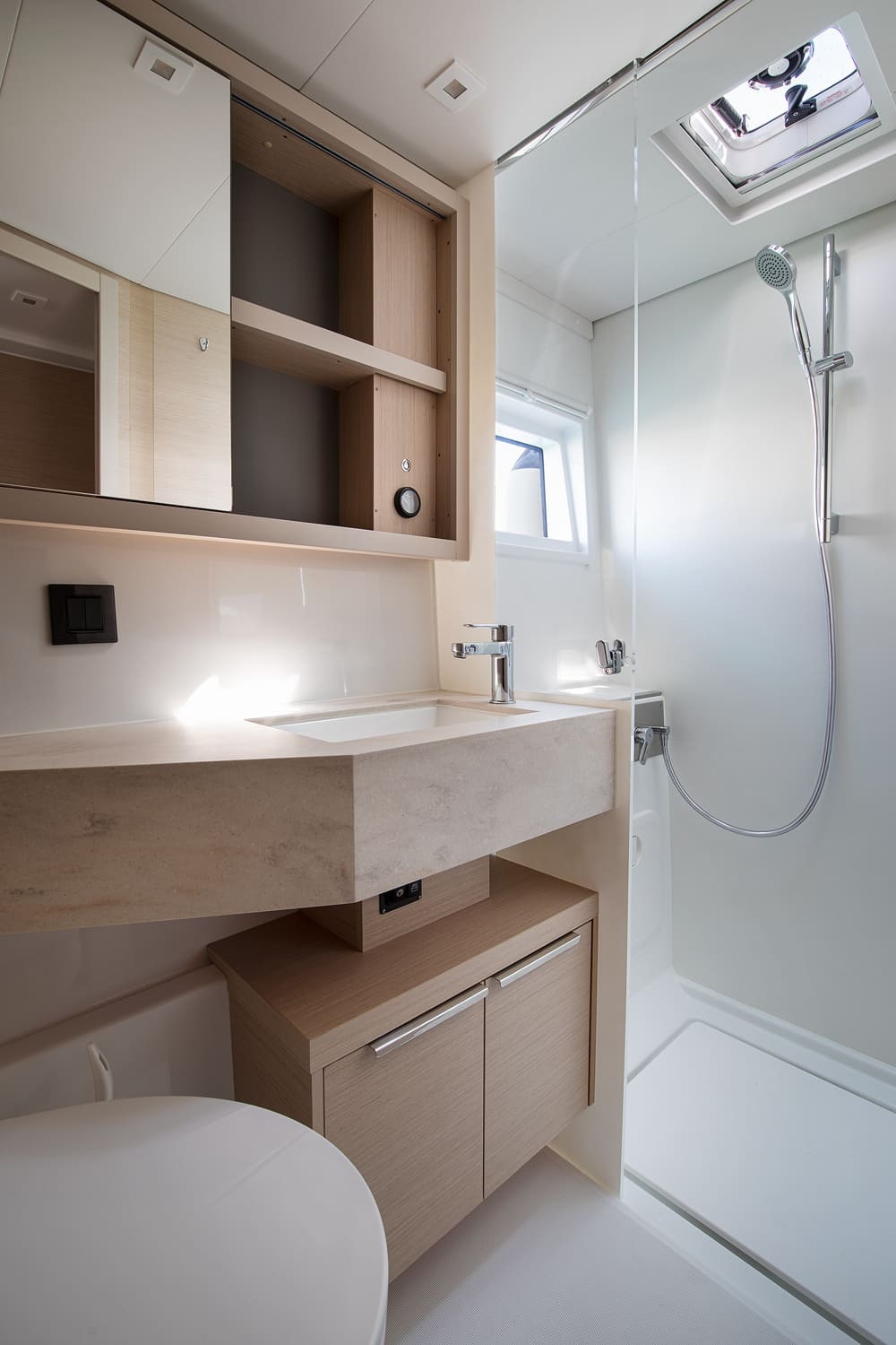 Shower cubicle and washbasin in a Lagoon 46 heads compartment, with mirrored cabinet and overhead hatch