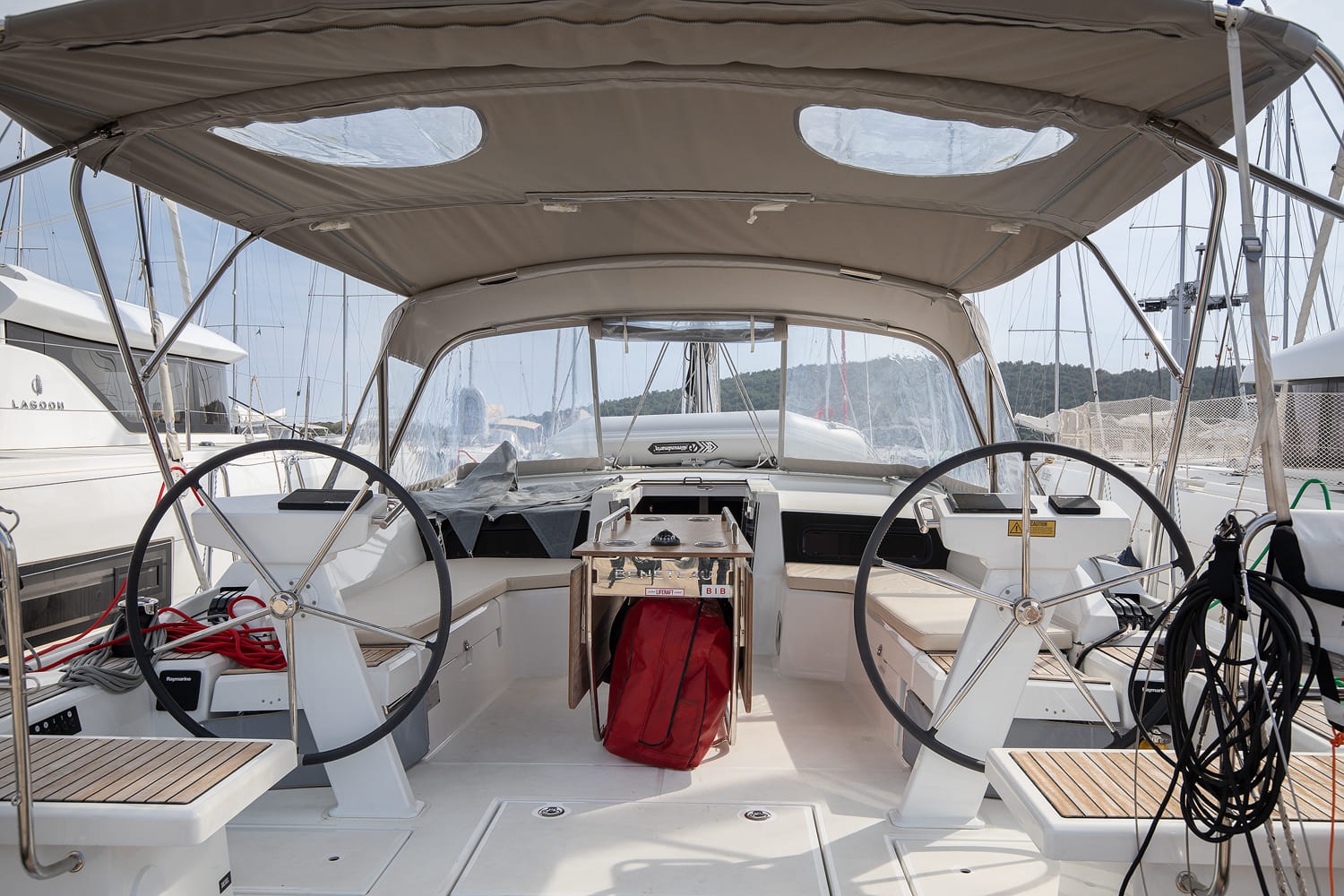 Cockpit under the bimini, with twin wheels, folding cockpit table and helm seats