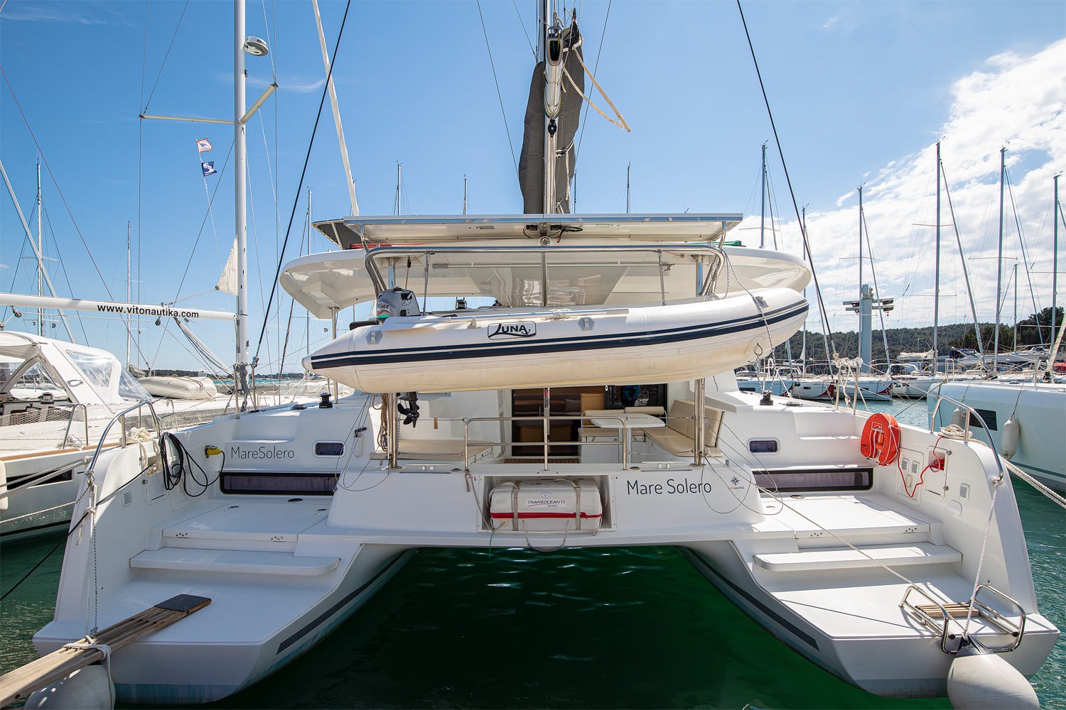 Stern view of Mare Solero with the tender stowed on davits above the bathing platforms and the liferaft canister between the two sugar-scoop steps.