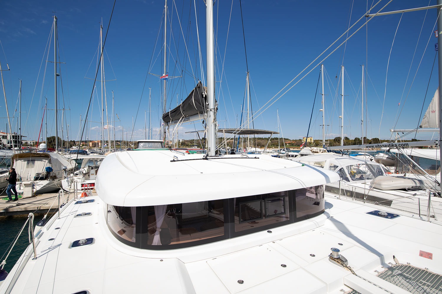 Foredeck of the Lagoon 42 looking aft over the coachroof, with the wraparound saloon windows and the mast above.