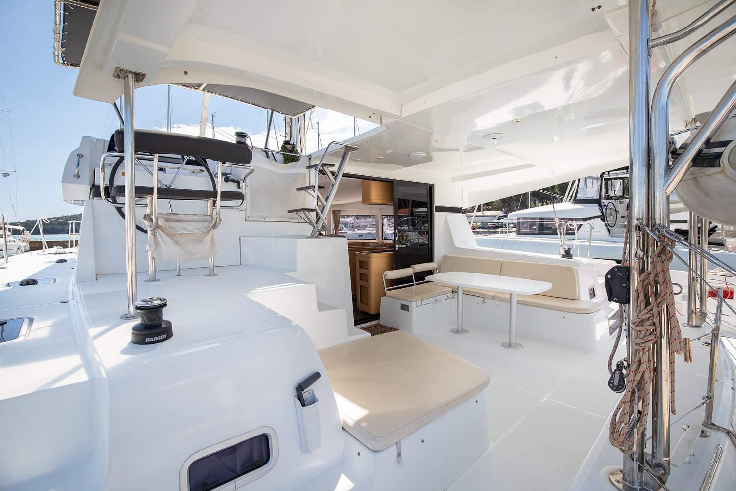 Cockpit under the bimini with dining table, upholstered bench seating and steps leading up to the helm.