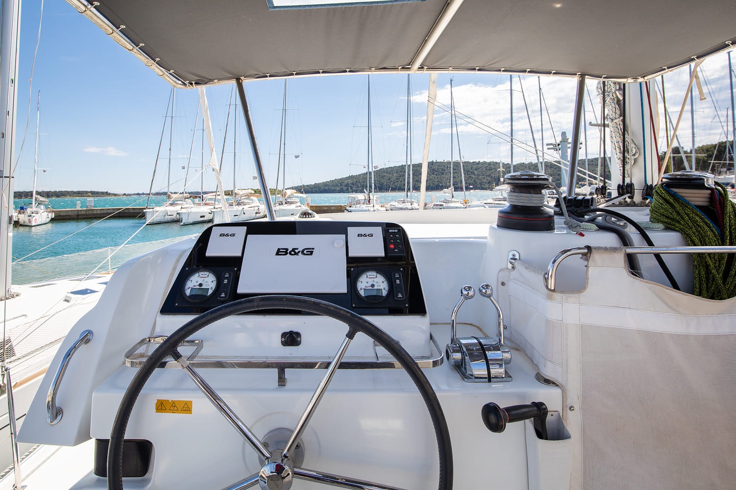 View forward from the helm seat: B&G chartplotter and engine gauges, with the winch and control lines within reach.