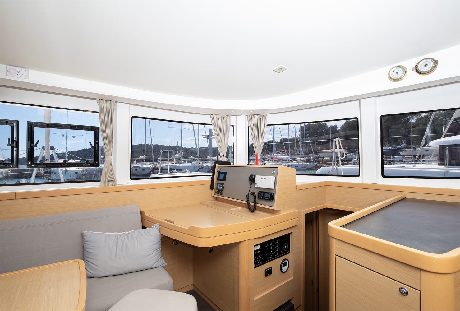 Navigation station with a B&G VHF radio and switch panel, set into the oak joinery beside the settee.