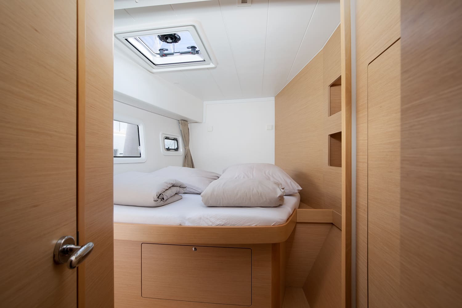 Double cabin seen from the doorway, with an overhead hatch, hull window and storage beneath the berth.