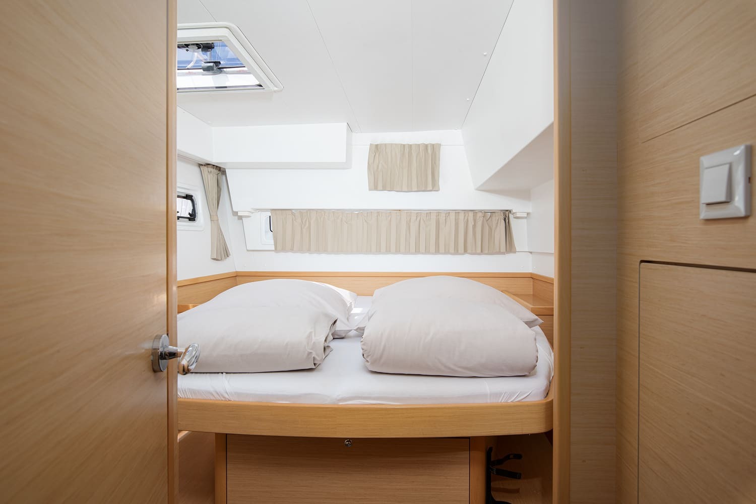 Forward double cabin with curtained hull windows, an overhead hatch and drawers beneath the berth.
