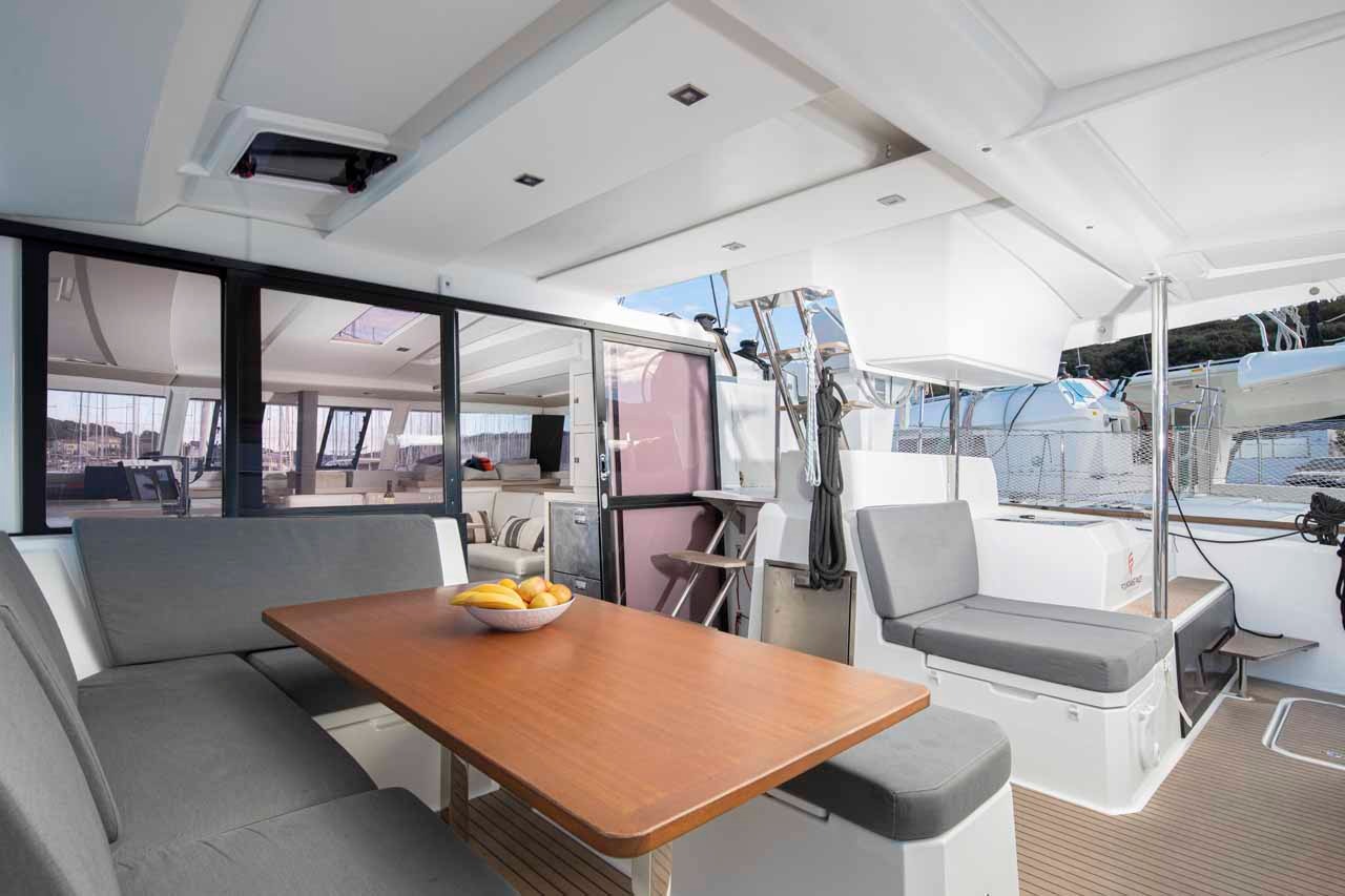 The cockpit of Follow the Sun with its teak table, cushioned bench seating and a cool box beside the helm steps.