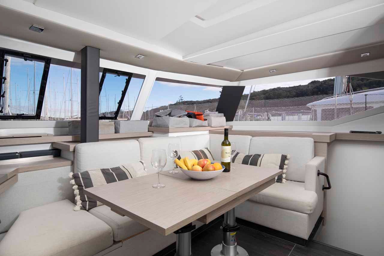 The saloon dining area of Follow the Sun, with a large table, corner seating and views out over the foredeck.
