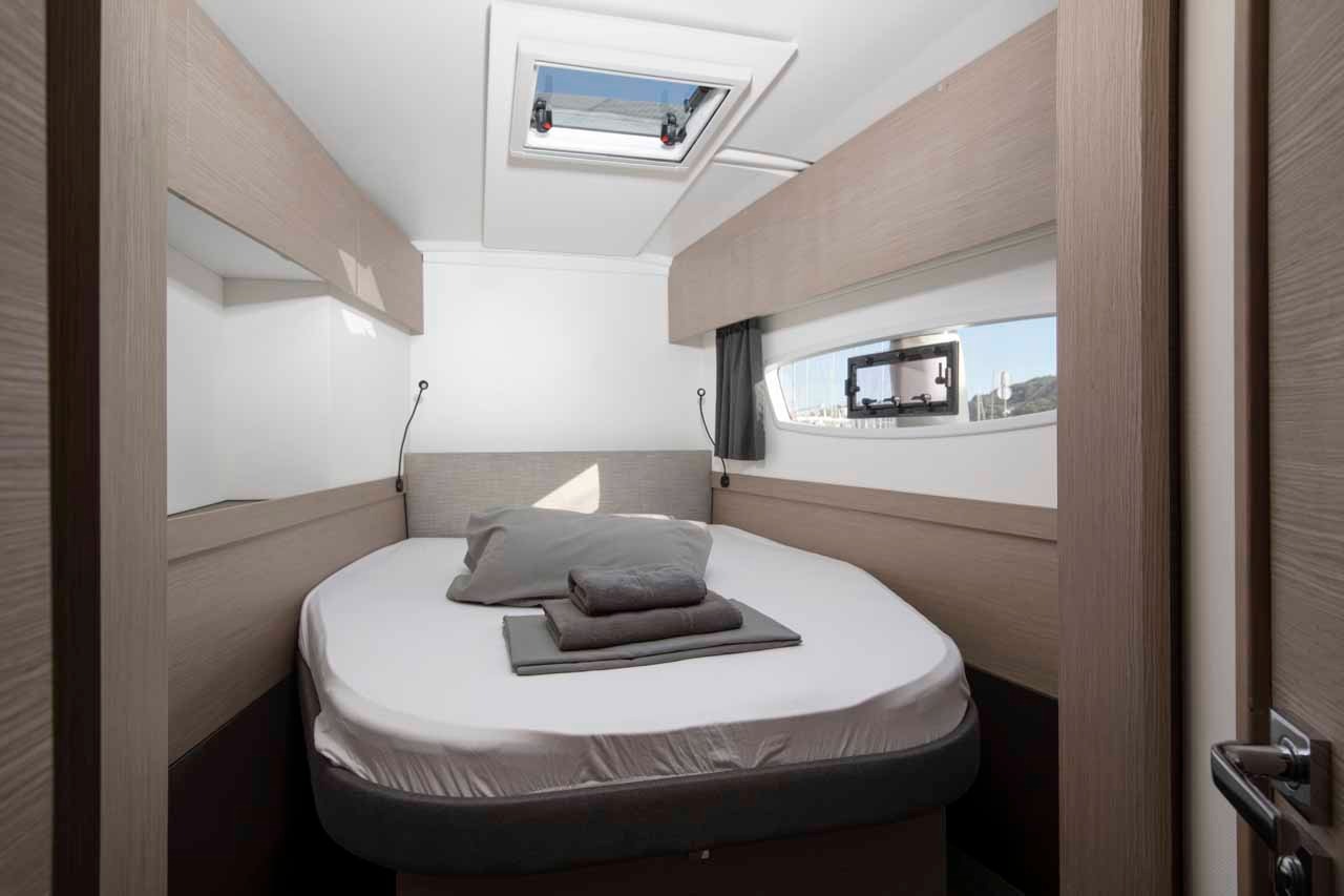 A double cabin aboard Follow the Sun, with a wide berth, overhead hatch, hull window and linen laid out ready.