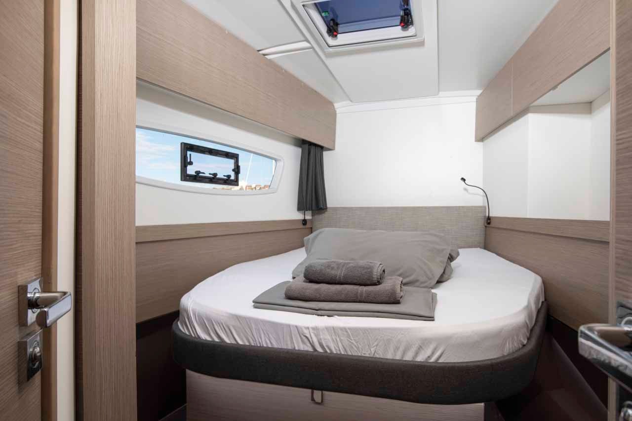 A double cabin aboard Follow the Sun, with a large berth, opening hull window and a washbasin just inside the door.