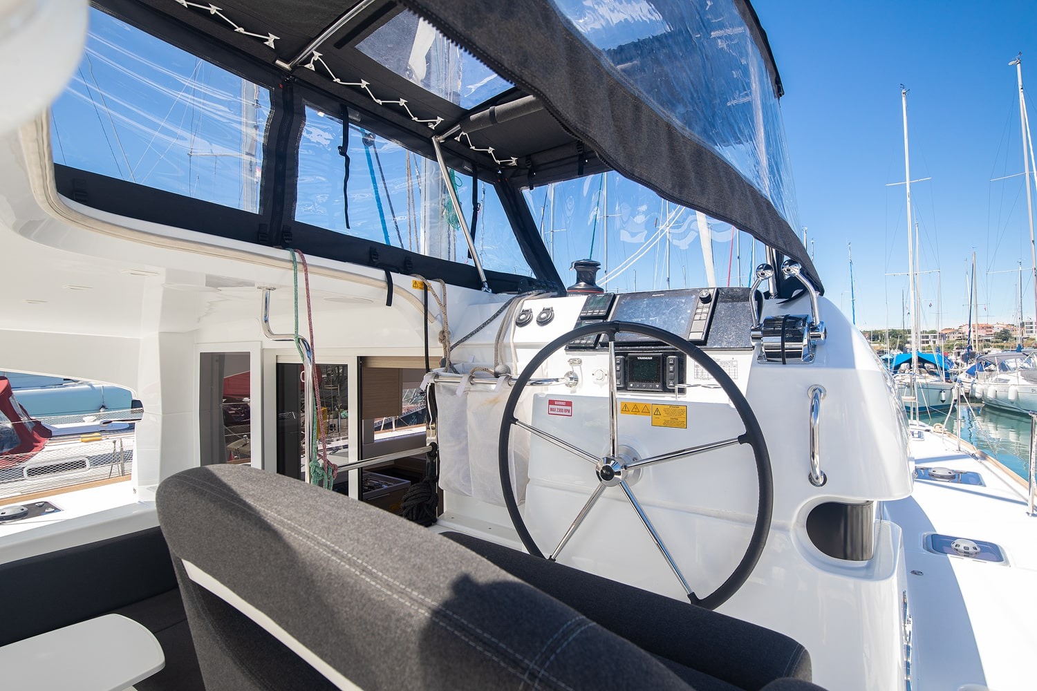 Helm station under the sprayhood, showing the wheel, chart plotter, engine controls and winch within reach of the helm seat