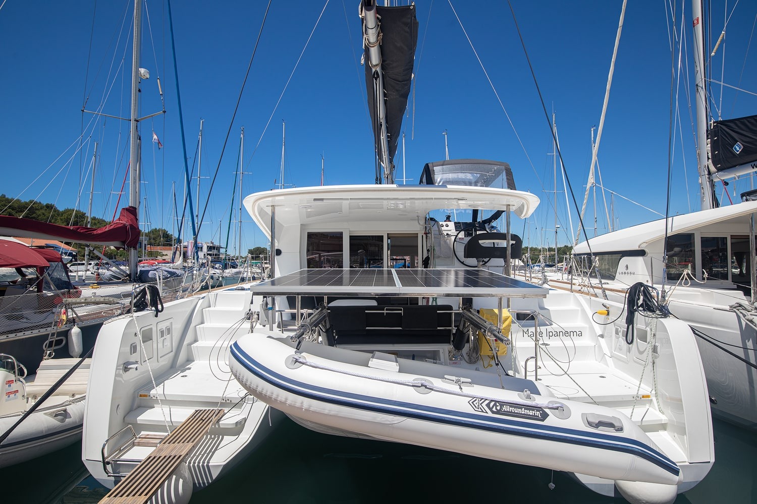 Stern view of the Mare Ipanema, with a solar panel over the aft deck, a tender on davits and boarding steps down to the pontoon