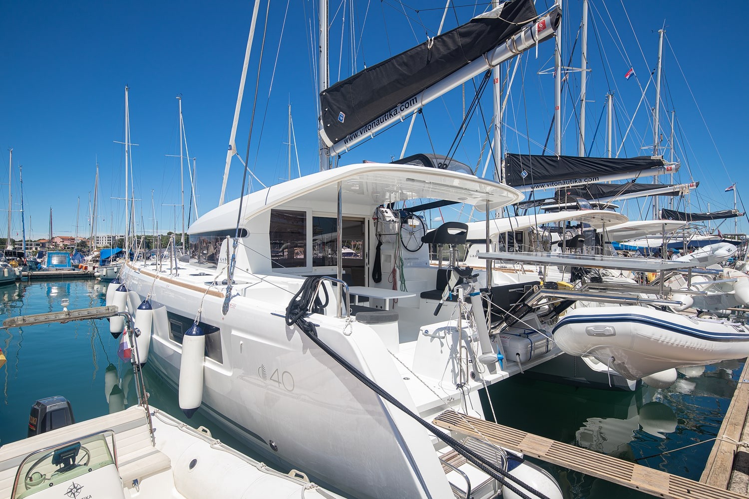 Mare Ipanema, a 2024 Lagoon 40 catamaran moored stern-to in ACI Marina Pomer near Pula, with fenders along the hull and the Lagoon 40 name on the topsides