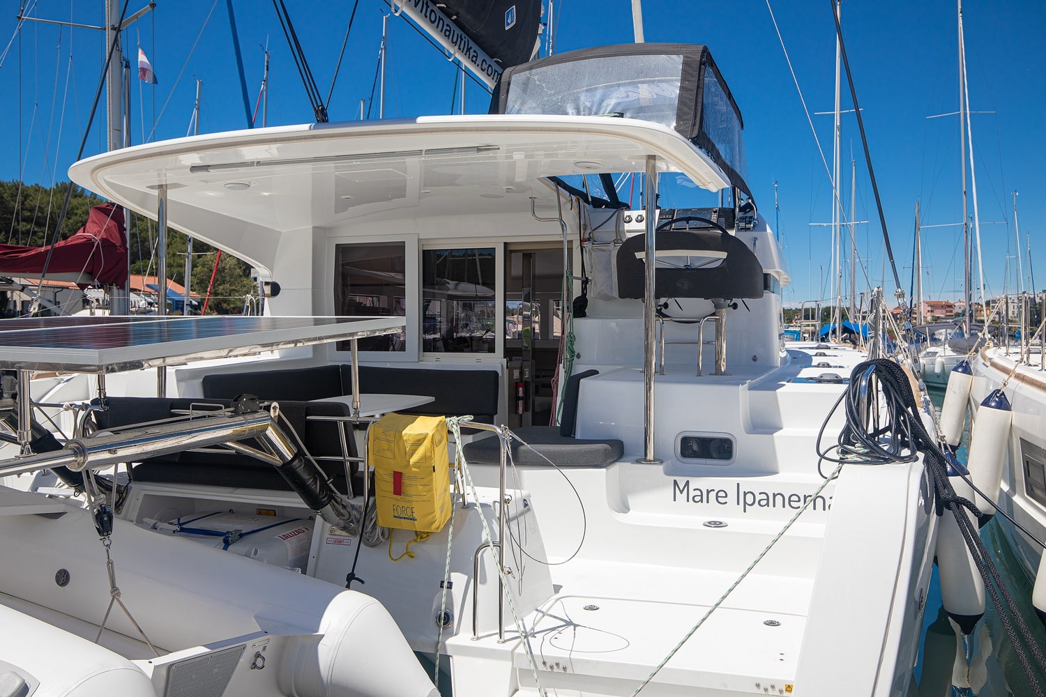 Aft cockpit and helm station of the Mare Ipanema, with the yacht name on the transom and the liferaft canister stowed on deck