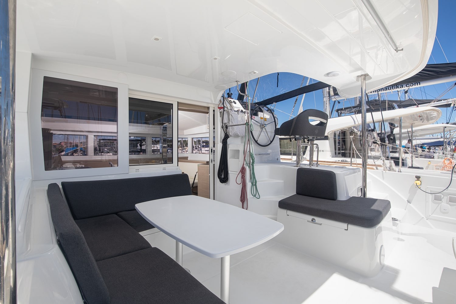 Covered cockpit with a large L-shaped bench, dining table and steps up to the helm, sheltered under the coachroof