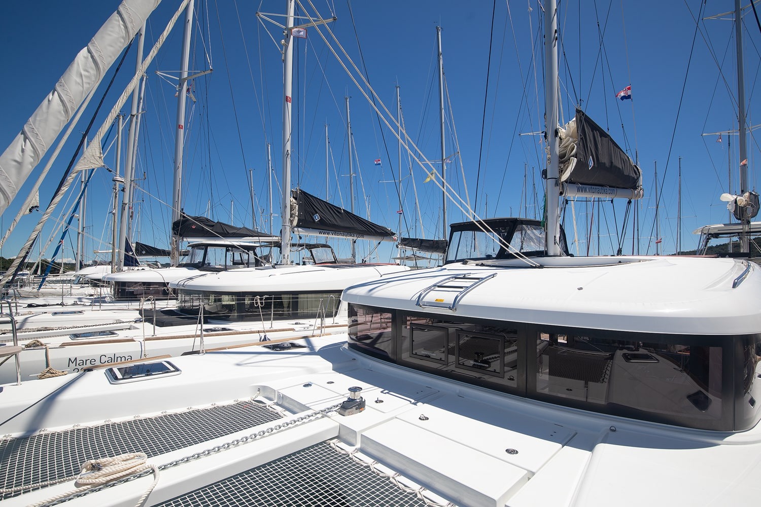 Foredeck and coachroof seen from the bow, with the hardtop, deck hatch and neighbouring catamarans in the marina