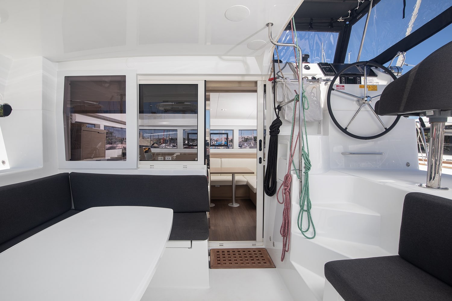Cockpit seating and dining table beside the sliding door to the saloon, with the helm steps and coiled lines to starboard