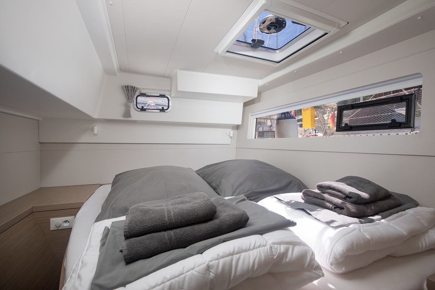 Double cabin with a made-up berth, overhead hatch, opening portlight and a hull window along the bed