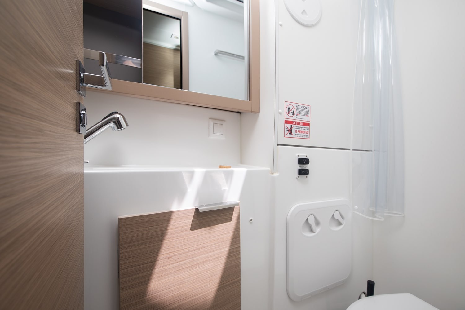 Second heads compartment with a washbasin, mirrored cabinet, shower curtain and electric toilet