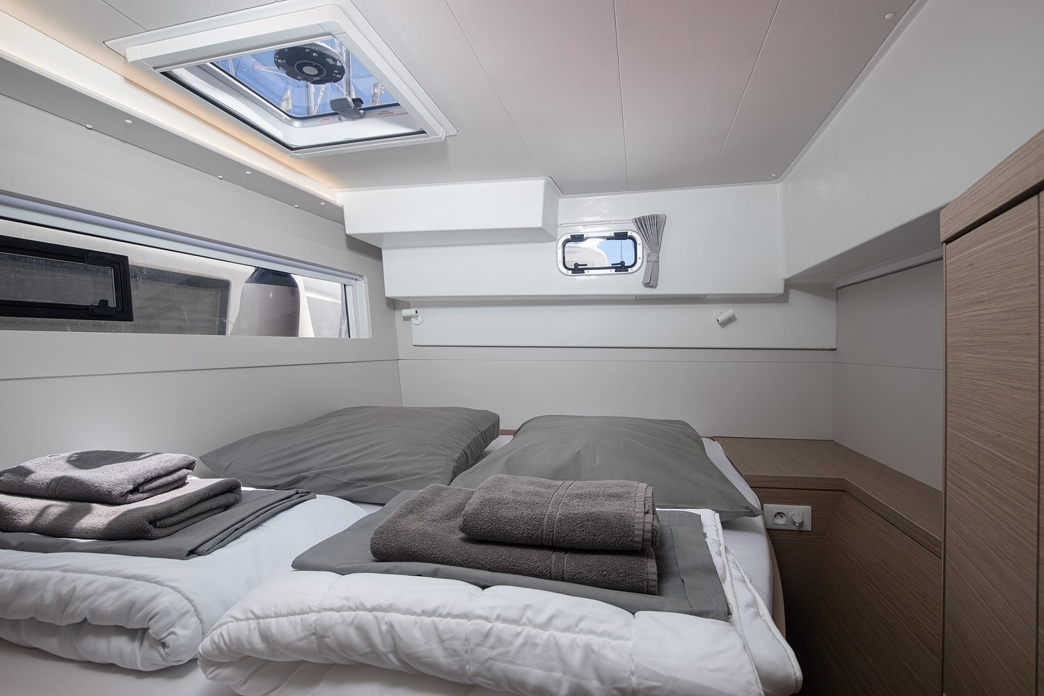 Double cabin with a made-up berth, wardrobe, overhead hatch and a hull window running the length of the bed