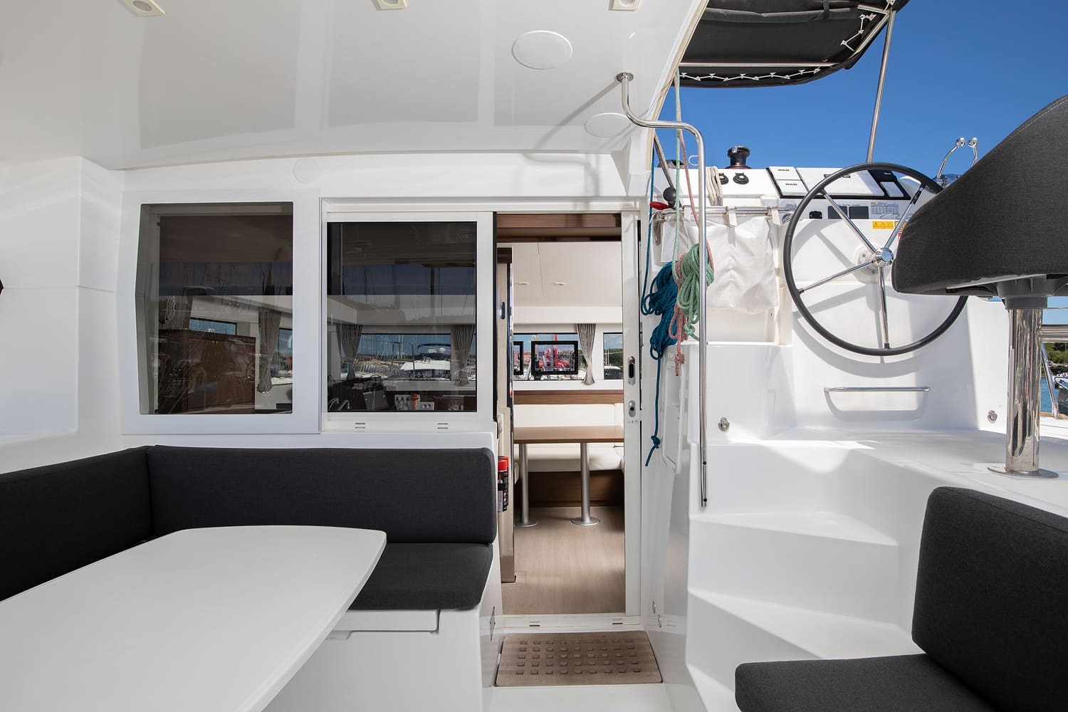 Yolo's cockpit with dining table and bench seating, the sliding door open to the saloon and steps up to the helm.