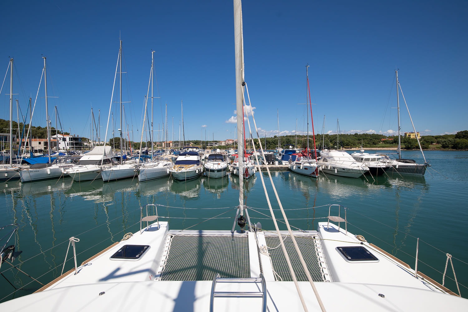 Foredeck of the Lagoon 40 with trampolines between the bows and the mast above, looking out across the marina.