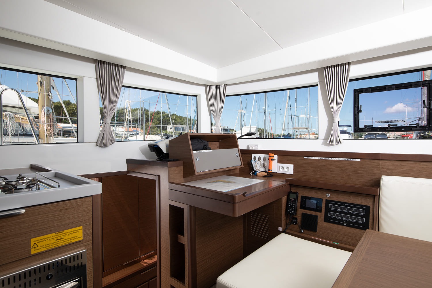 Saloon looking towards the chart table and navigation panel, with the galley cooker to the left and windows all round.