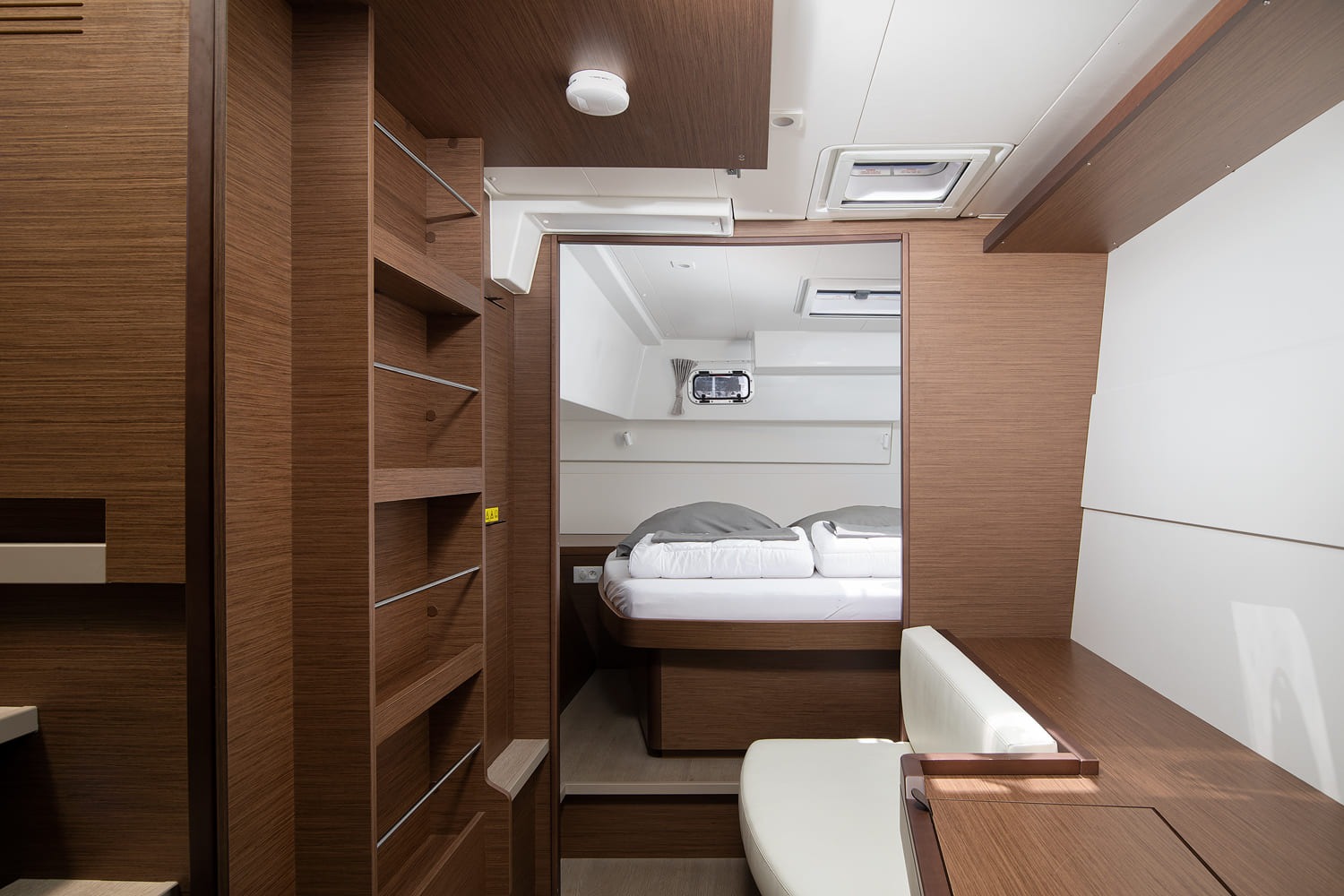 Double cabin in the hull with the berth made up, shelving in the passage and a hatch overhead.