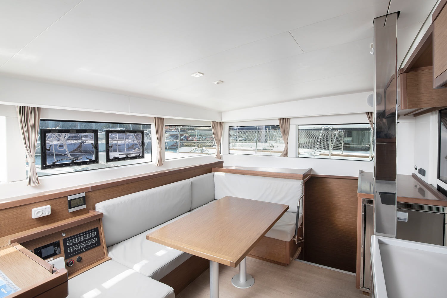 Saloon dining table and white upholstered settee below the panoramic windows, with the switch panel alongside