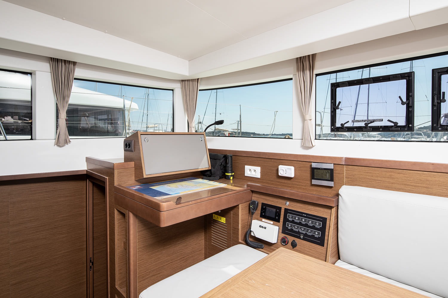 Chart table with B&G VHF radio, switch panel and folding chart top, below the saloon windows