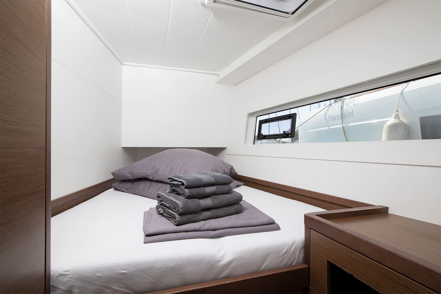 Double cabin with made-up berth, folded towels and a long hull window looking out over the pontoon