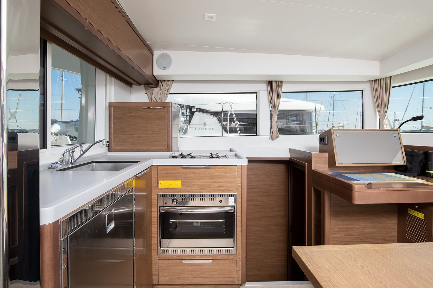 Galley with stainless sink, three-burner gas hob, oven and fridge, next to the chart table
