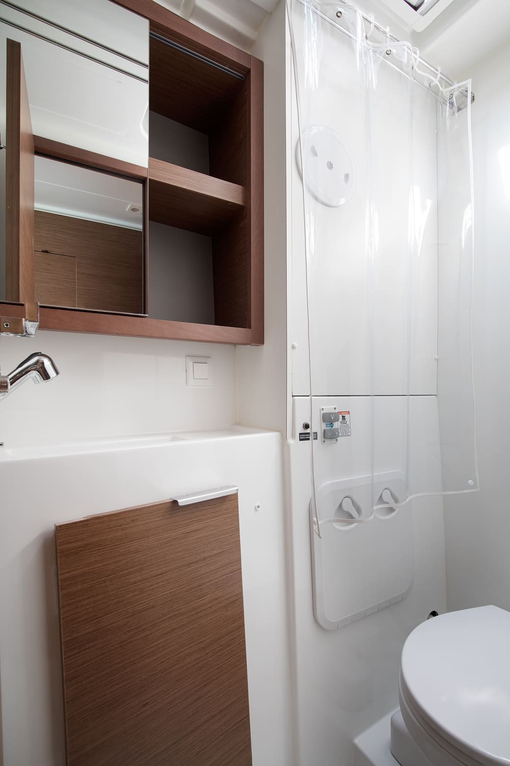 Heads seen from the shower side, with sink, mirrored cabinet with open shelves and electric toilet
