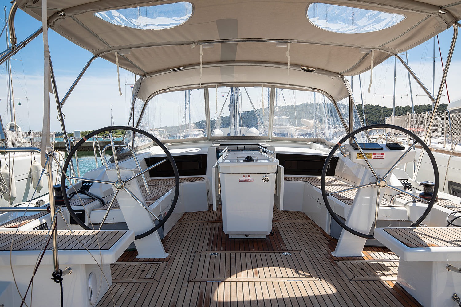 View aft across the cockpit, twin wheels and instrument pods framing the marina