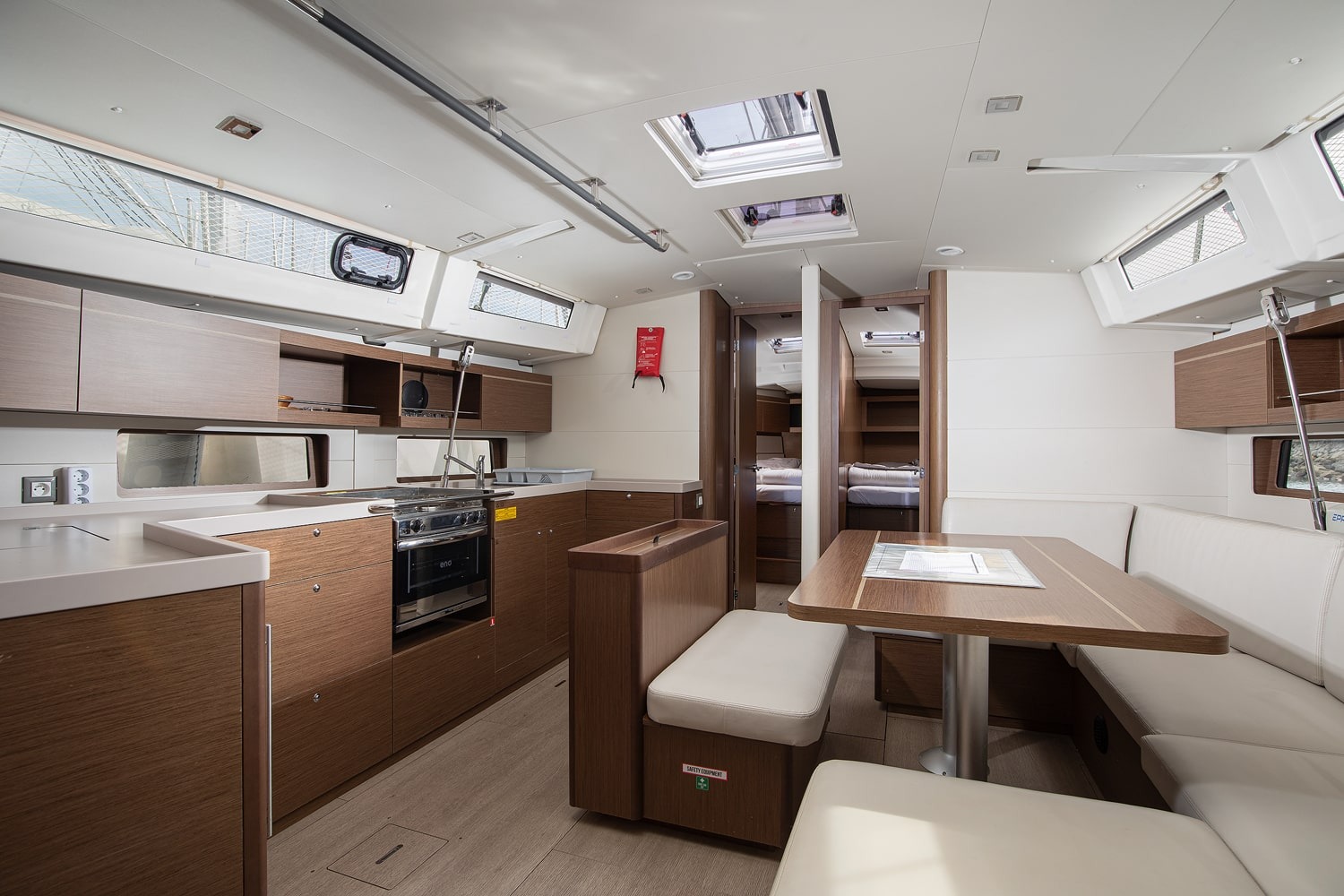 The saloon of Amore di Mare, with a wooden dining table, upholstered seating and light oak joinery