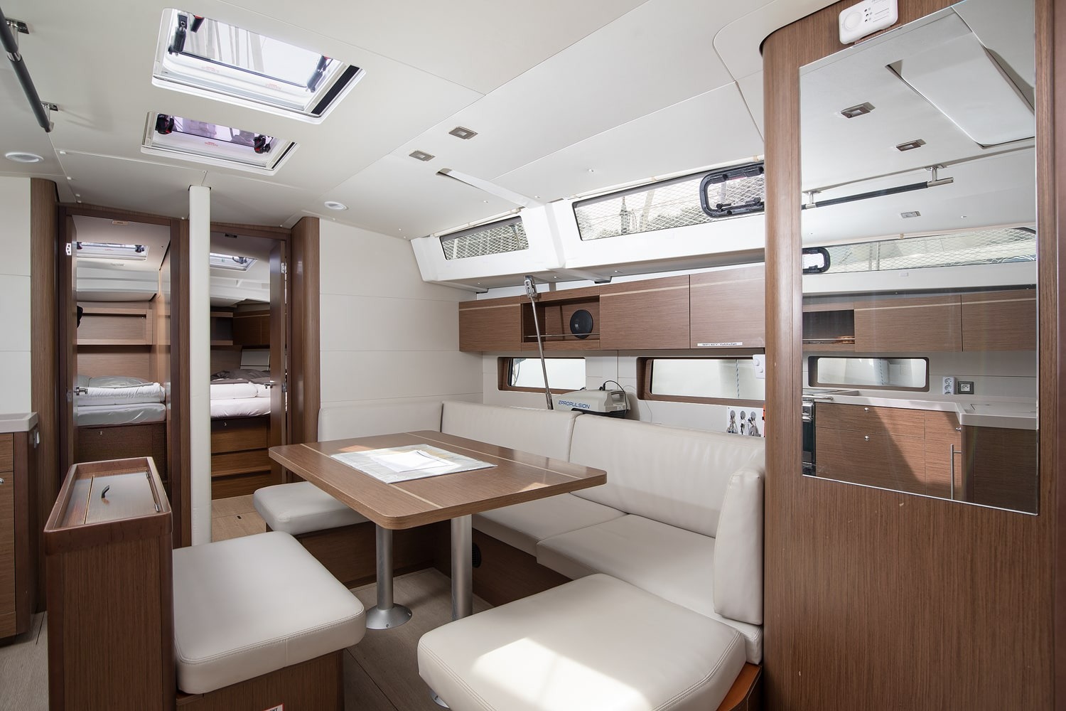 The saloon of Amore di Mare from the companionway, with the dining table, galley worktop and overhead hatches