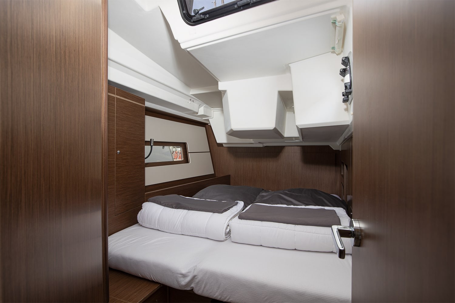 A twin-berth cabin aboard Amore di Mare, with two single beds and dark wood joinery