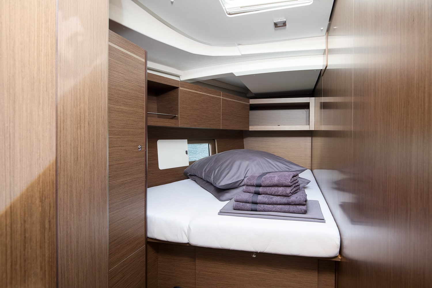 Double cabin aboard the Vento di Mare, with made-up berth and wood-panelled hull side.