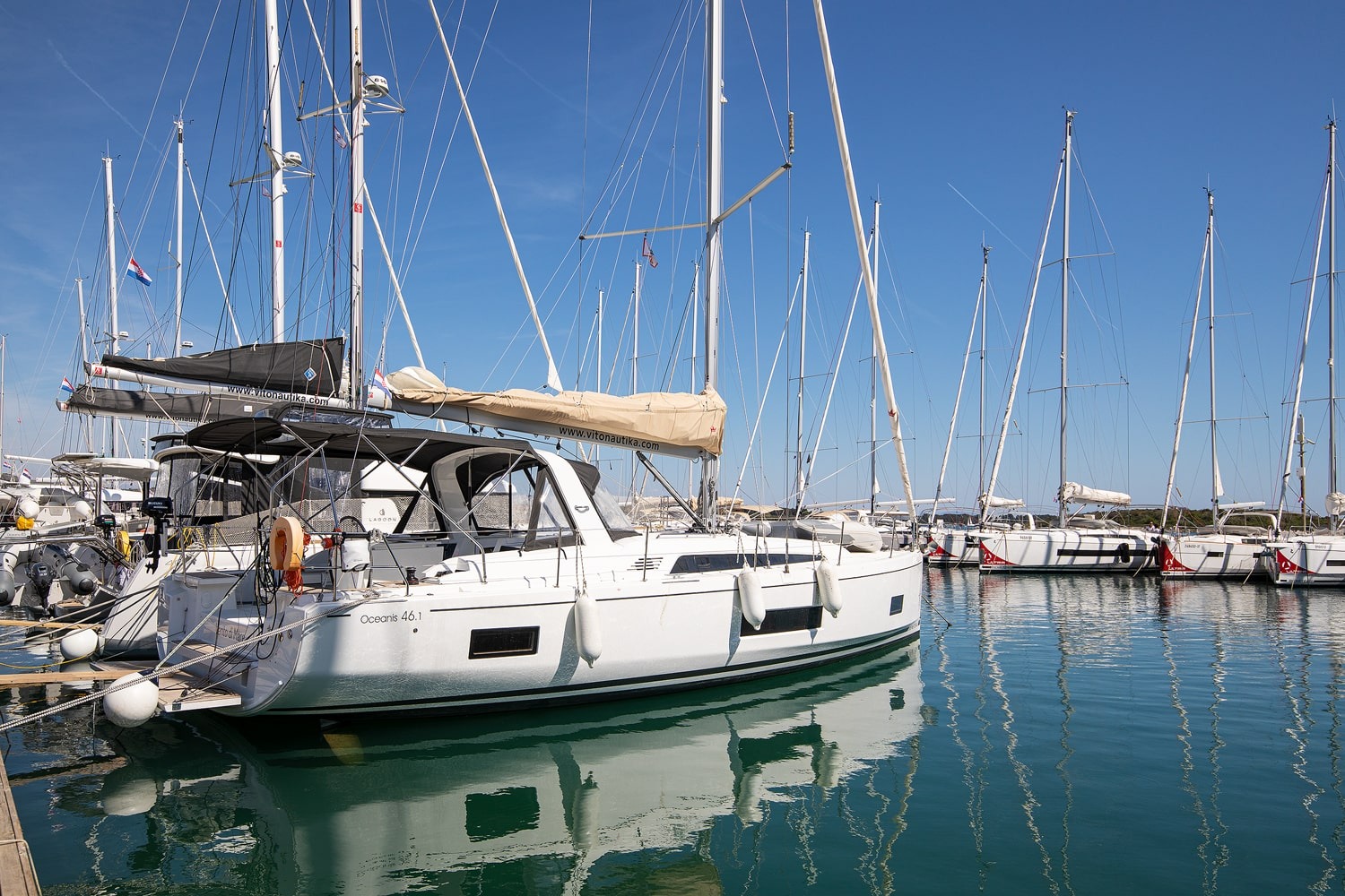 Side view of the Vento di Mare at her berth, white hull and mast against the marina at Pomer.