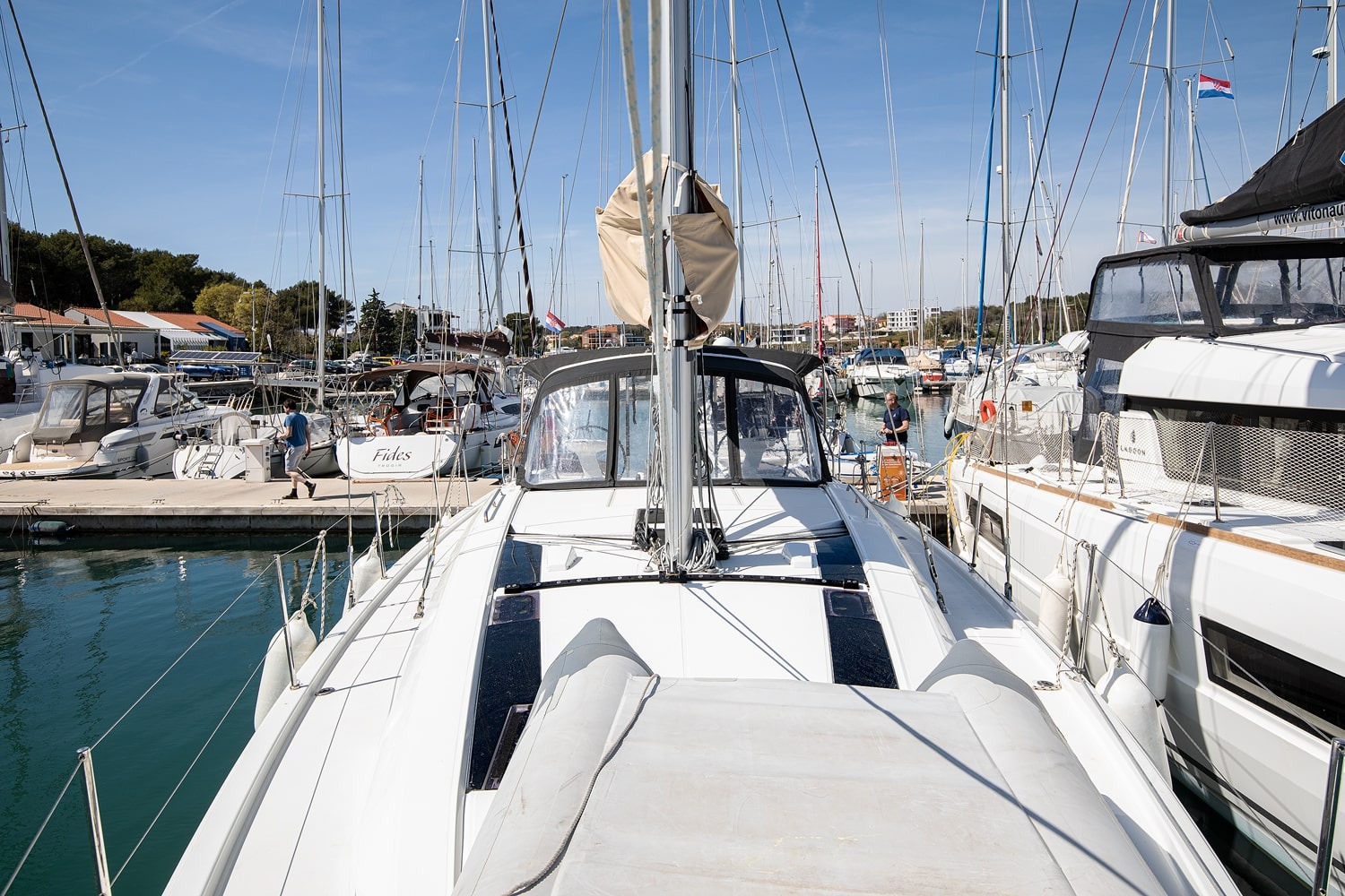 Looking forward along the deck of the Vento di Mare from the cockpit, mast and marina beyond.